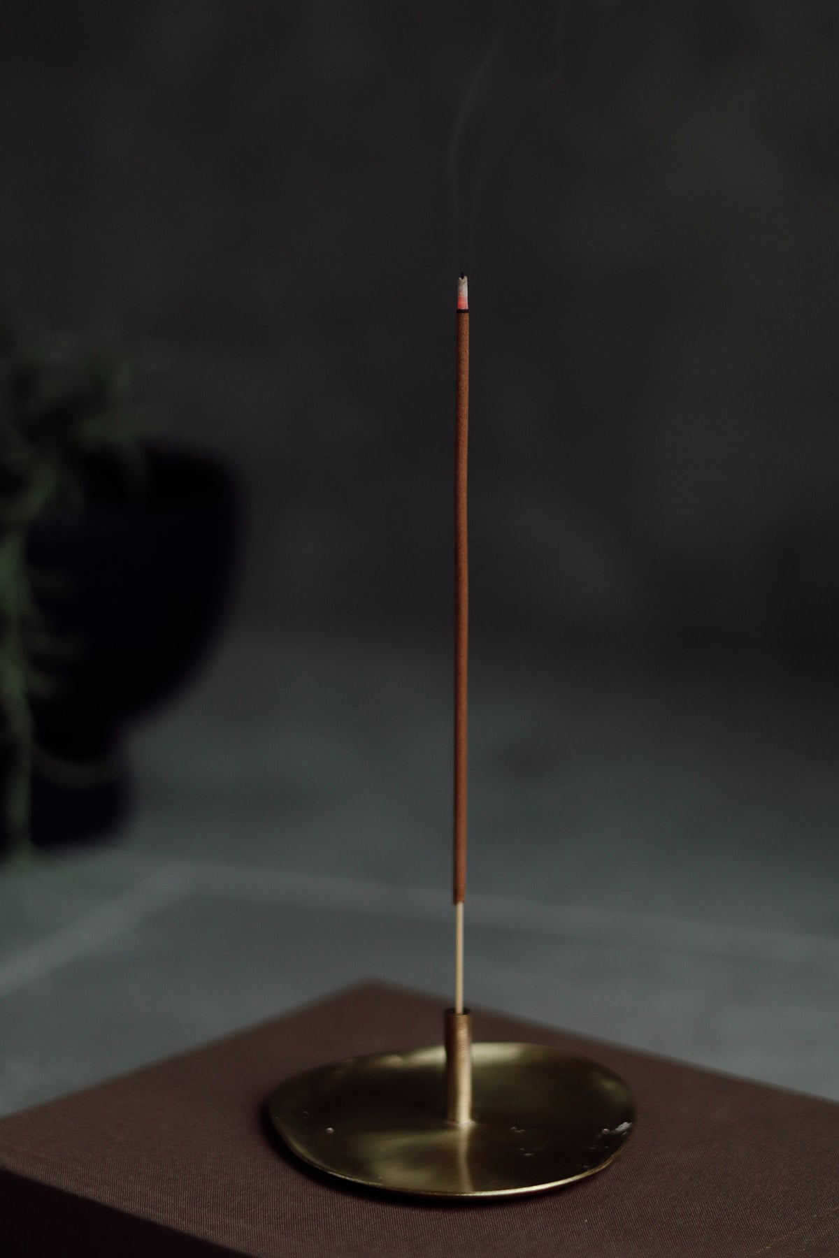 Incense stick on a brass holder with a dark background