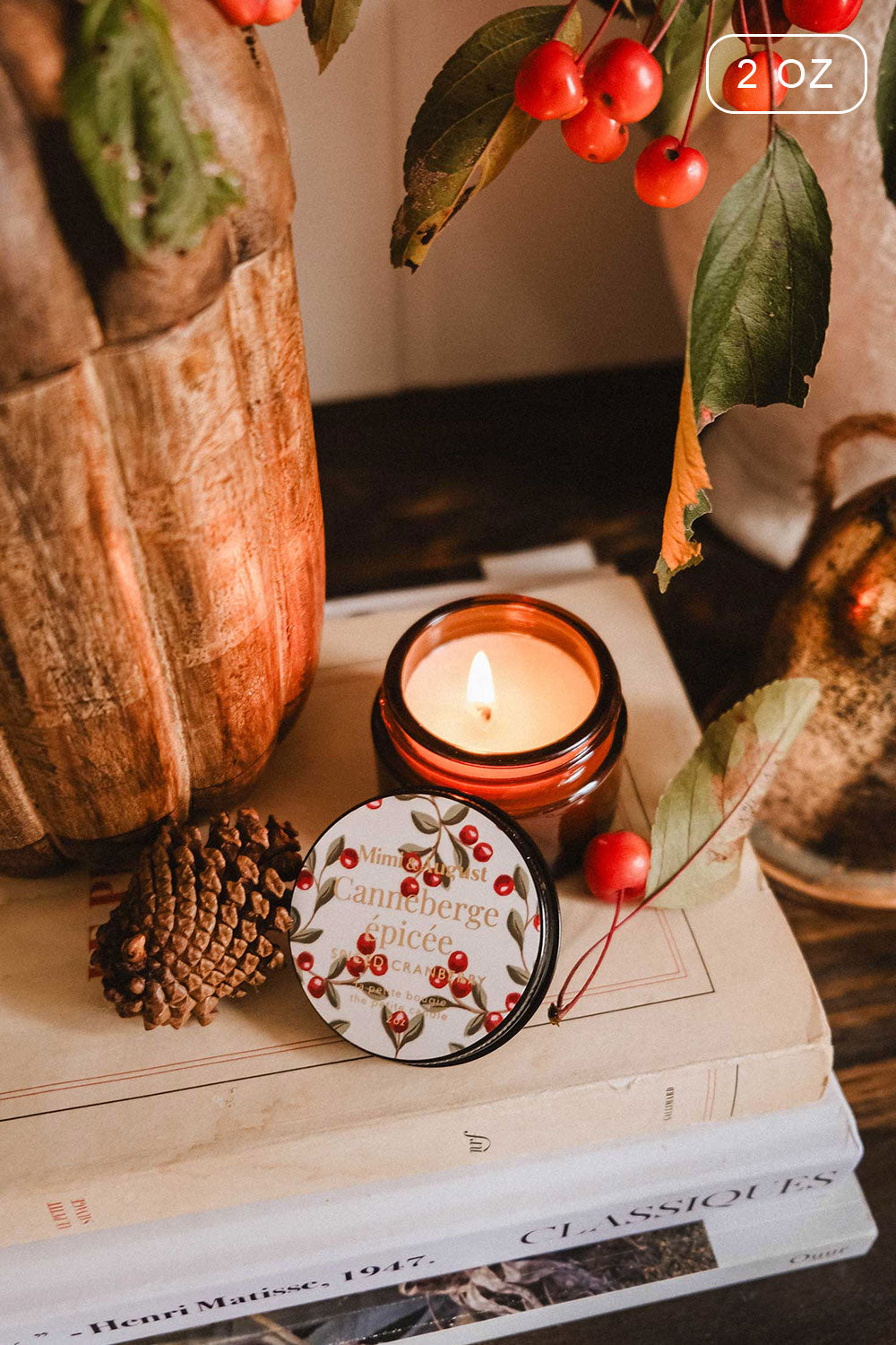 2 oz Spiced Cranberry Christmas Candle by Mimi & August and decorative box on books with a branch of berries