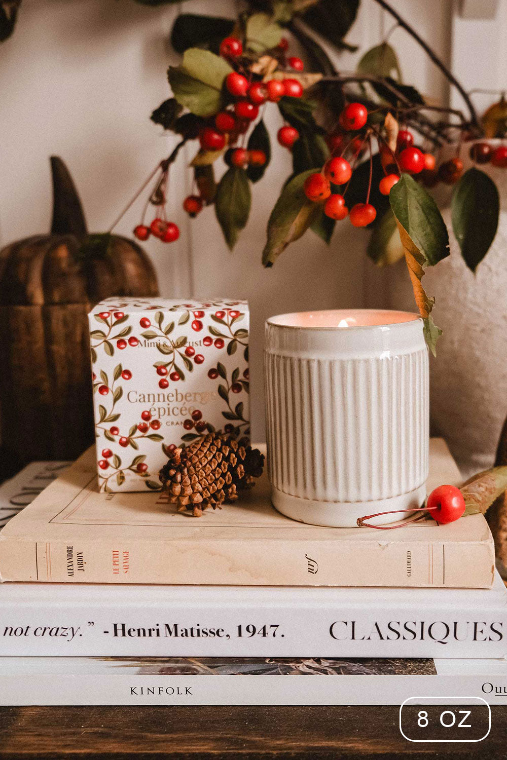 8 oz Spiced Cranberry Christmas Candle by Mimi & August and decorative box on books with a branch of berries