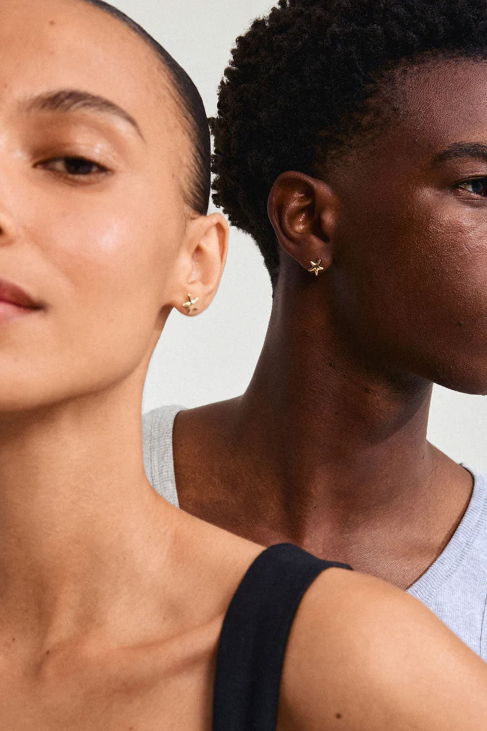 Two people wearing gold earrings BACOOR-GOLD from Pilgrim against a neutral background