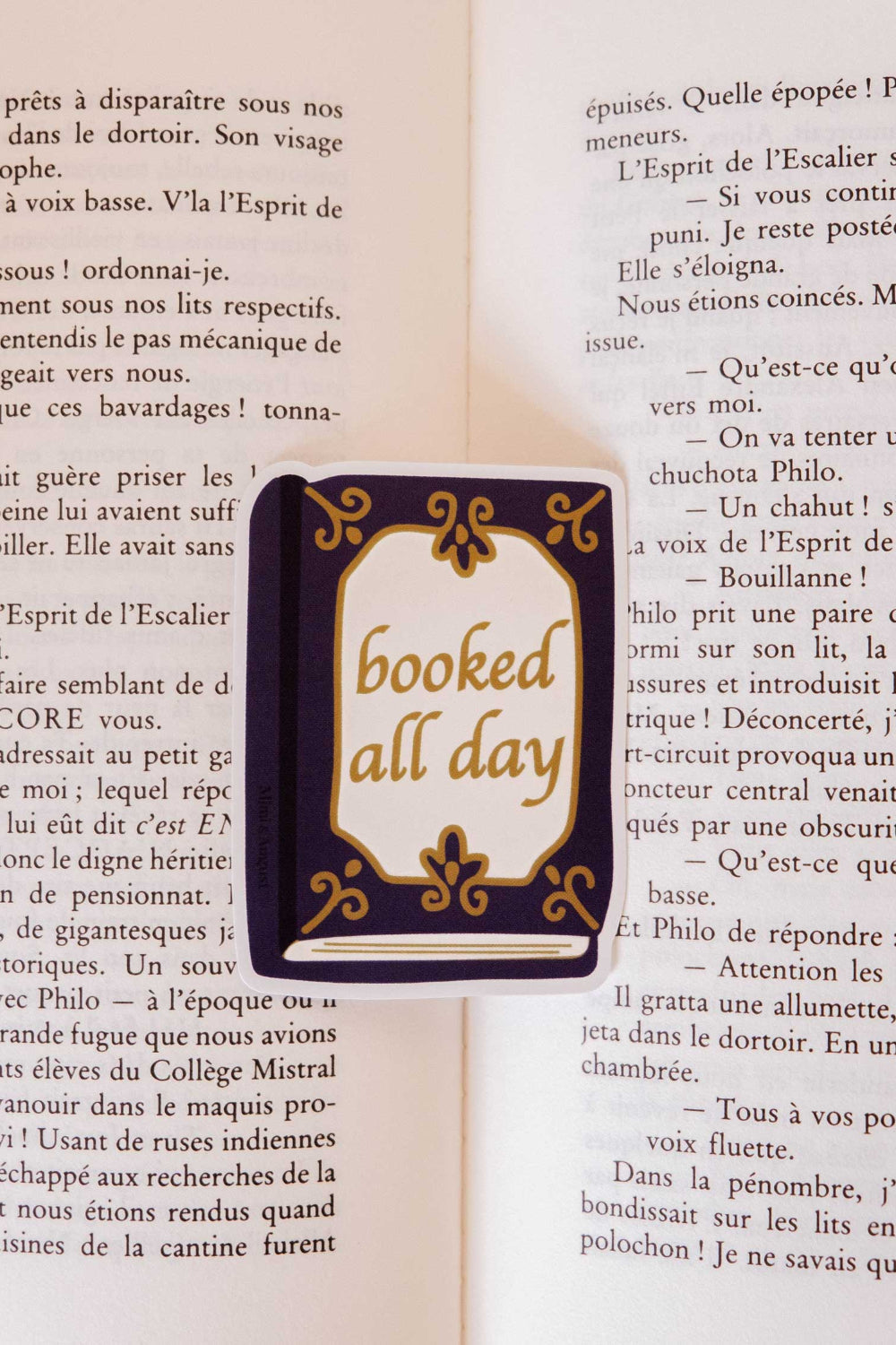 Small book sticker with 'booked all day' from mimi and august on a page of an open book