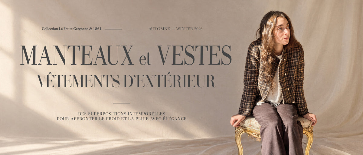 Une femme est assise sur une chaise à structure dorée devant un fond beige texturé, portant un manteau à carreaux bruns sur un haut blanc et un pantalon ample brun grisâtre. Un grand texte à gauche indique « MANTEAUX & VESTES », accompagné d’un texte de collection plus discret au-dessus.