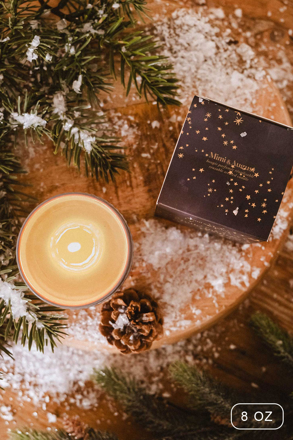 8 oz Shooting Star Christmas Candle by Mimi and August with a packaging on a wooden surface with decorative elements