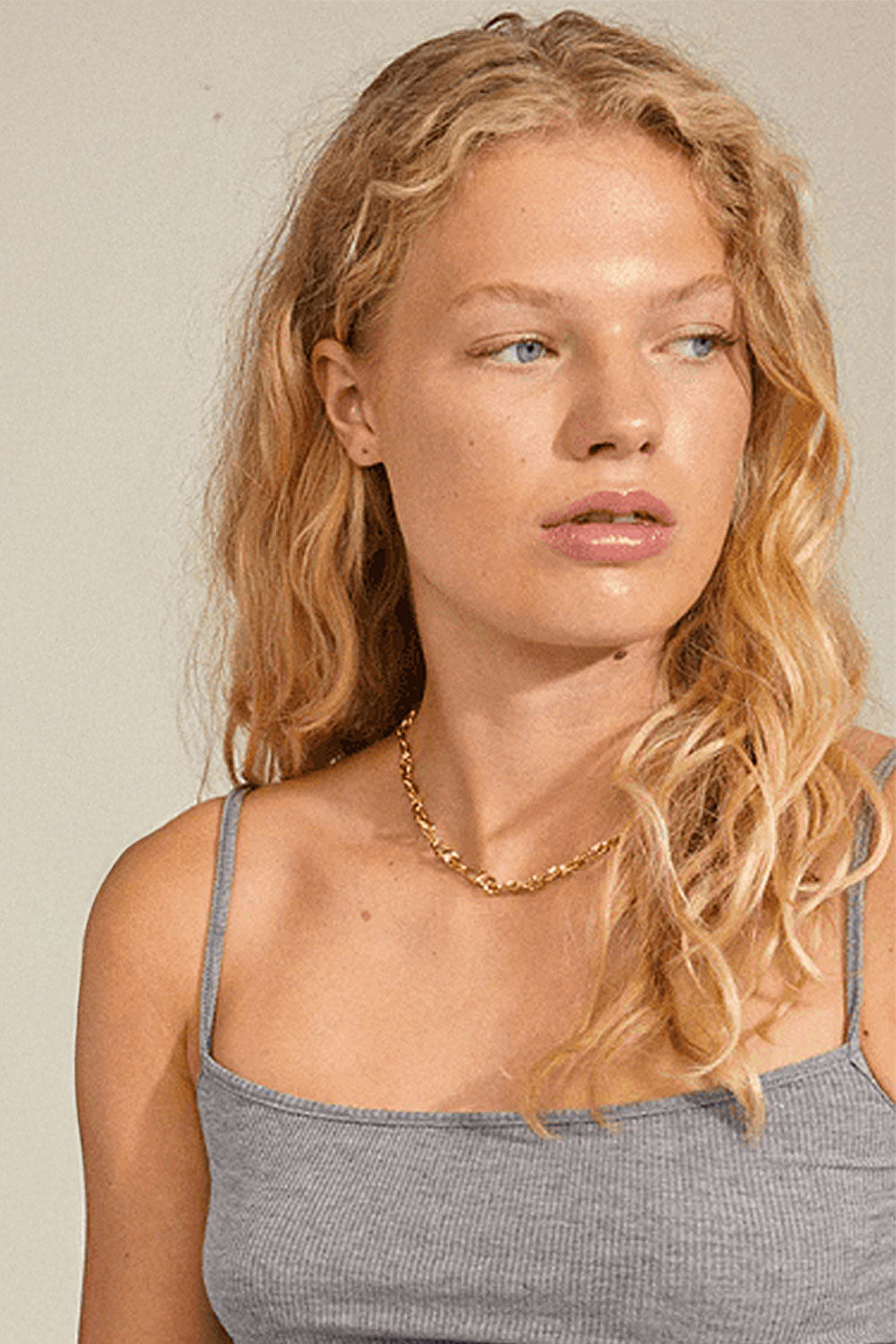 Woman wearing a gold necklace CHIFENG GOLD by Pilgrim against a neutral background