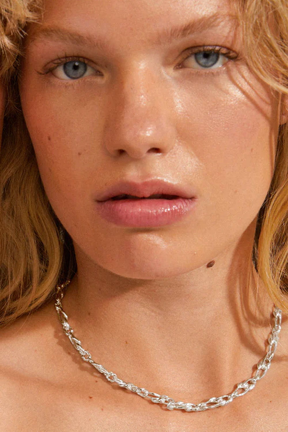 Close-up of a person wearing a silver chain necklace CHIFENG-SILVER by Pilgrim with a blurred background