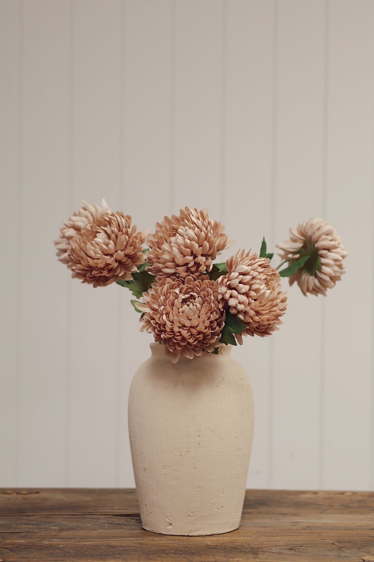 Beige vase with artificial beige chrysanthemum flowers stem with green leaves, at boutique la maison garçonne in montreal.
