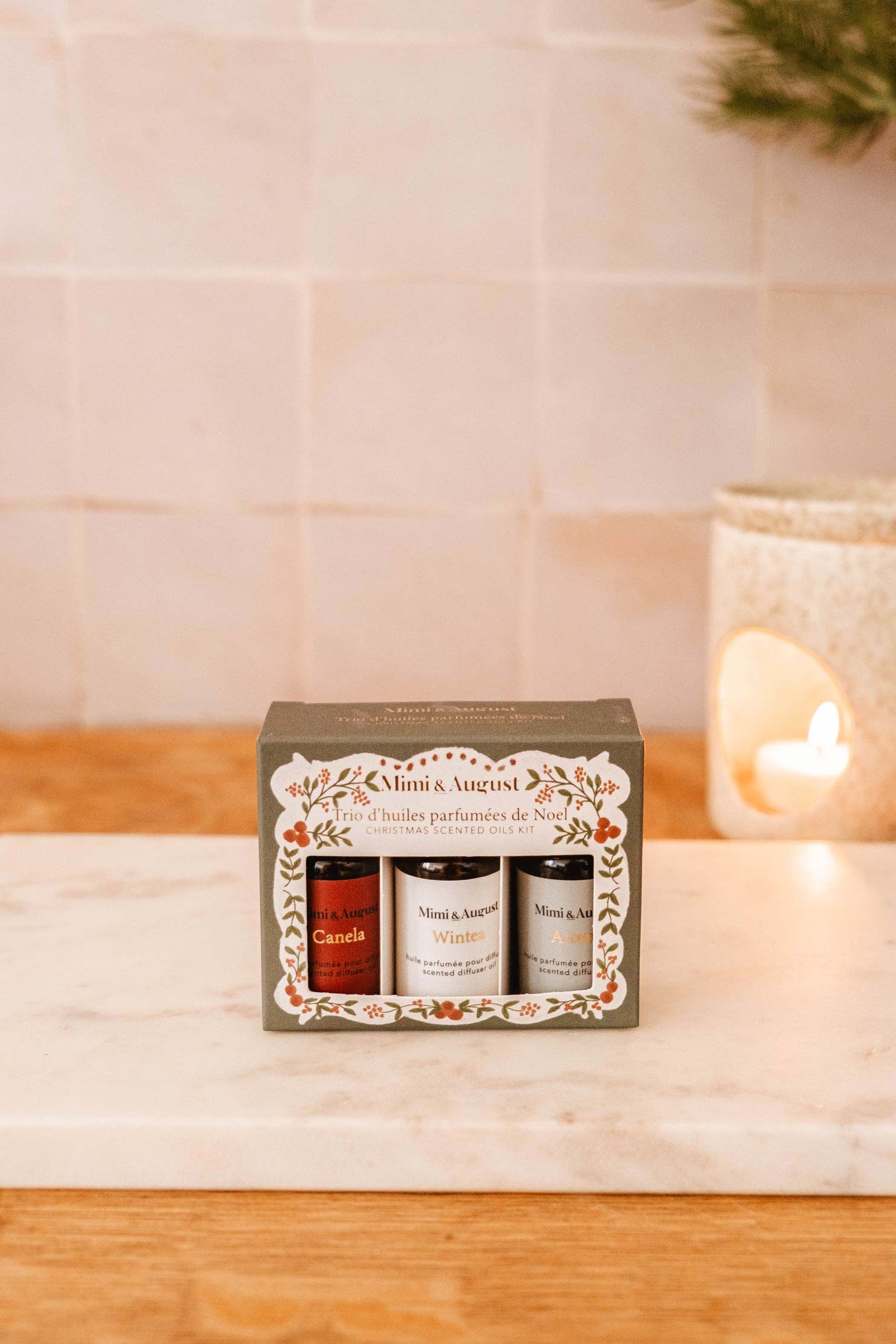 Christmas Scented Oils Trio by Mimi and August in a decorative box on a beige surface with Christmas decorations.