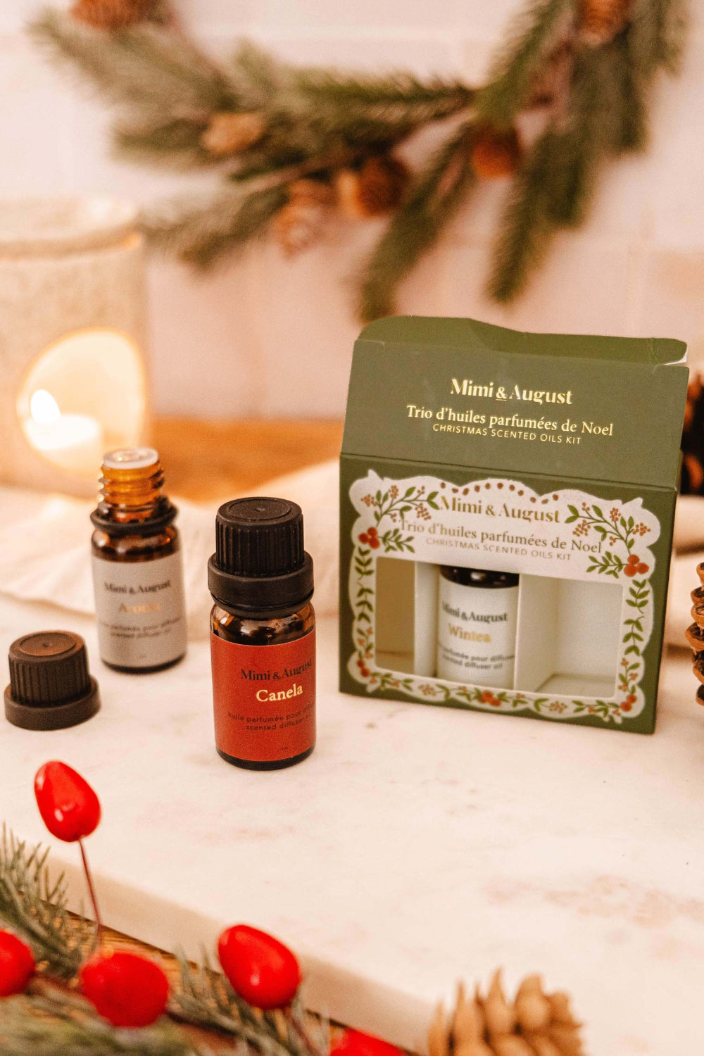 Christmas Scented Oils Trio by Mimi and August in a decorative box on a beige surface with Christmas decorations.