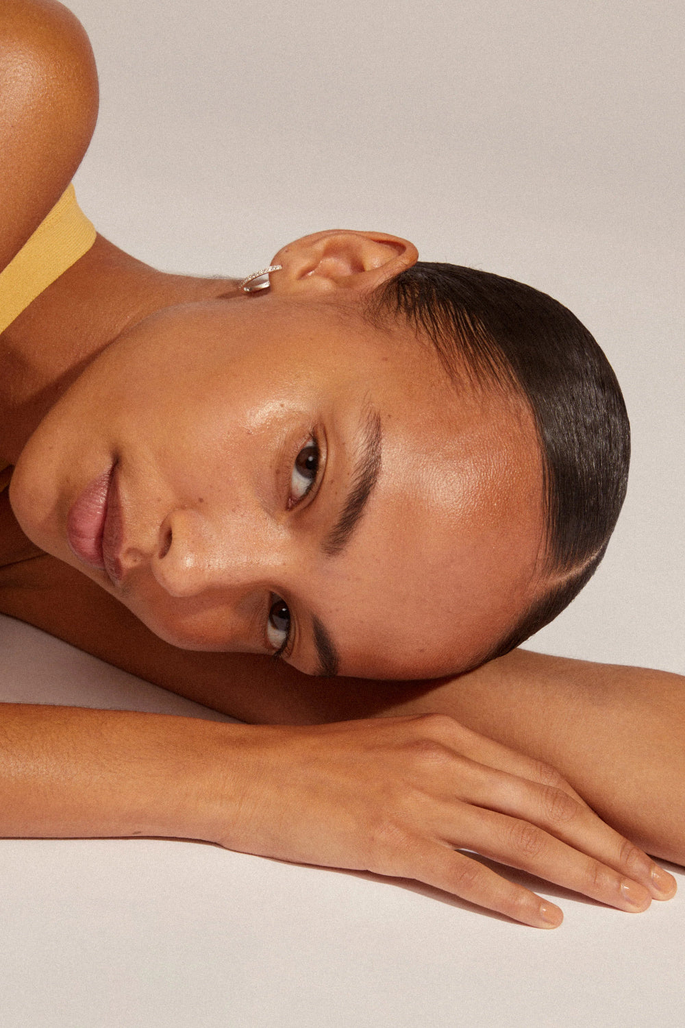Close-up of a woman wearing Ebna silver from Pilgrim, a gold hoop earring with stones details