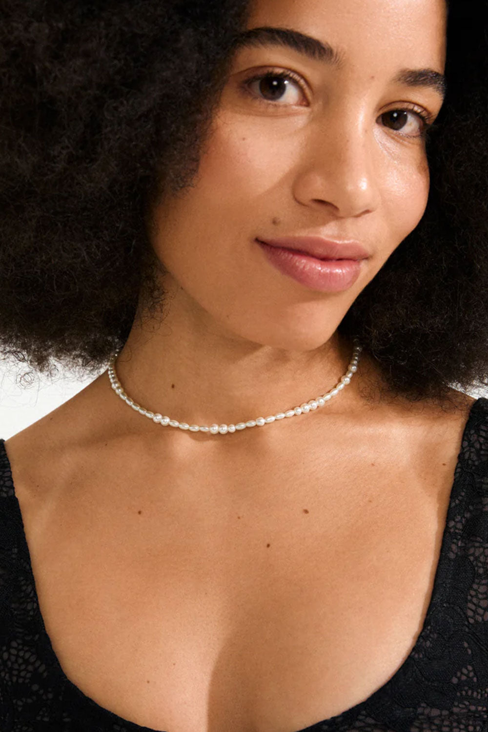 Woman wearing a pearl necklace ELLIANA-GOLD by Pilgrim against a neutral background