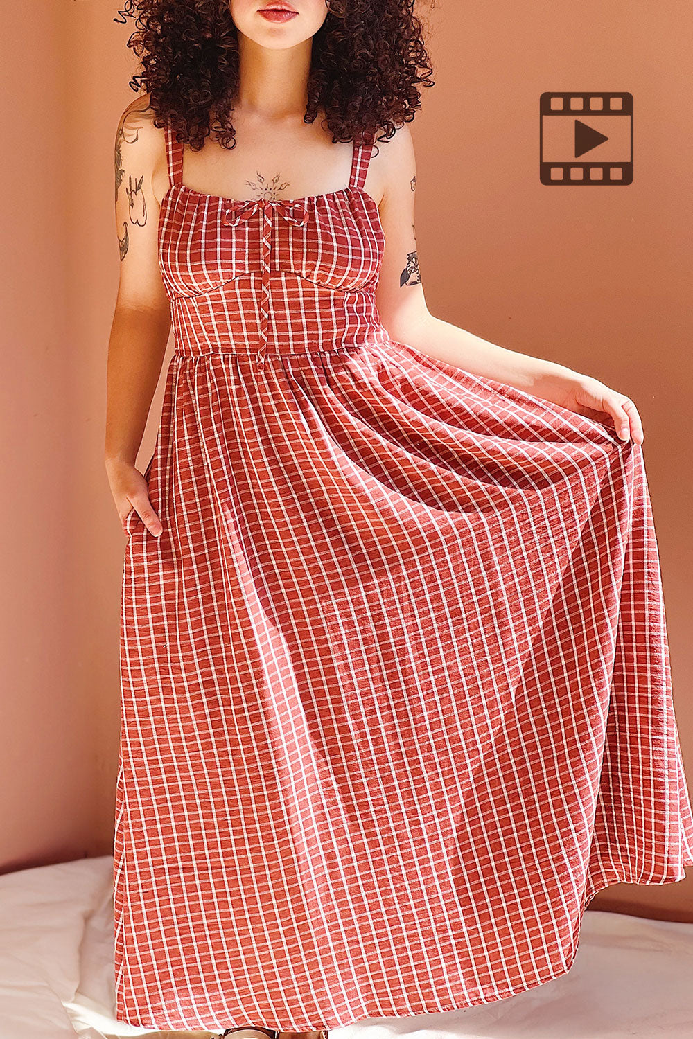 Photo of a mannequin wearing the Red checkered dress Kono against a light pink wall.