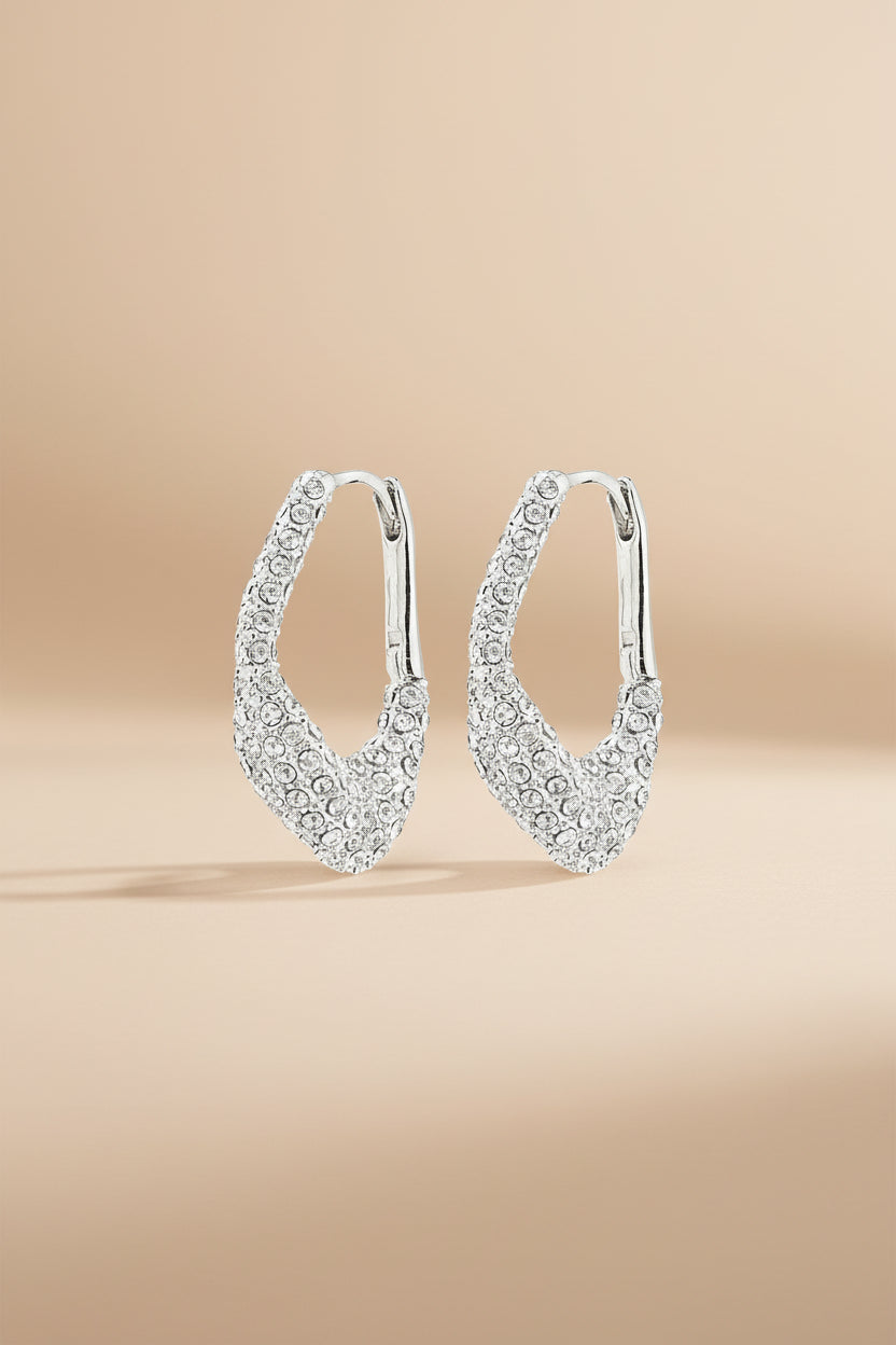 Pair of silver hoop earrings with embedded stones on a beige background