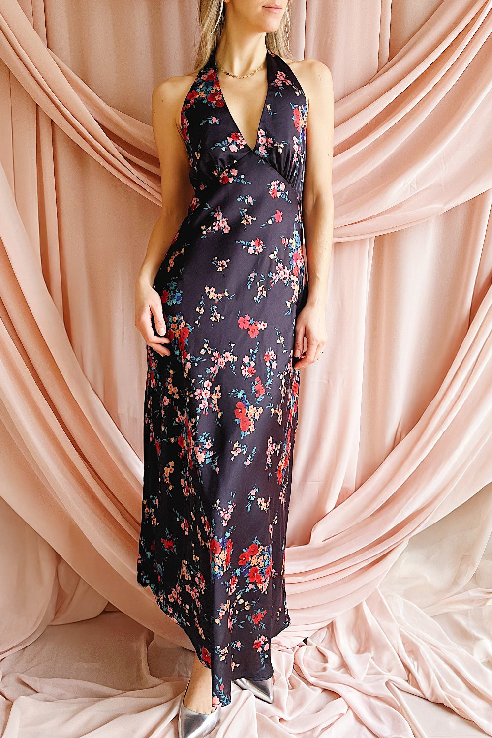 Woman wearing a floral dress against a pink draped curtain background
