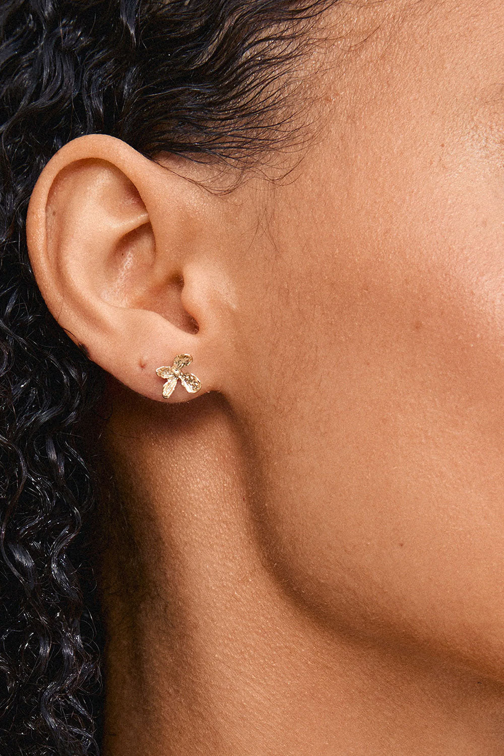 Close-up of a woman wearing AGLAIA, a gold flower-shaped earring from Pilgrim La petite garçonne Montreal