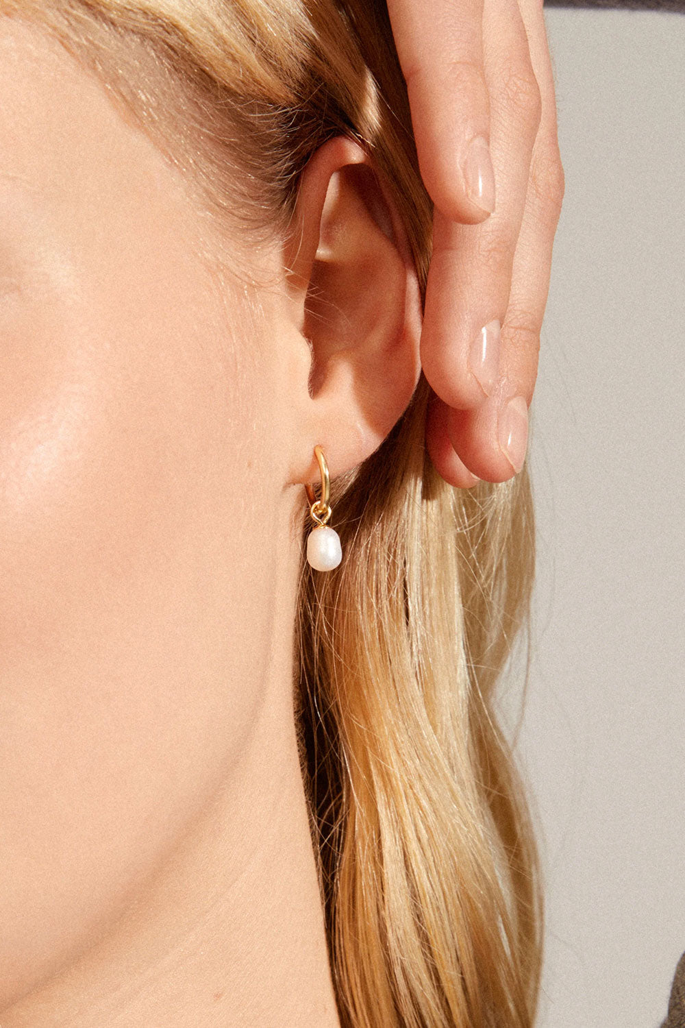 Close-up of an ear wearing a gold earring with pearl BOKARO from Pilgrim available at la petite garçonne in Montreal.