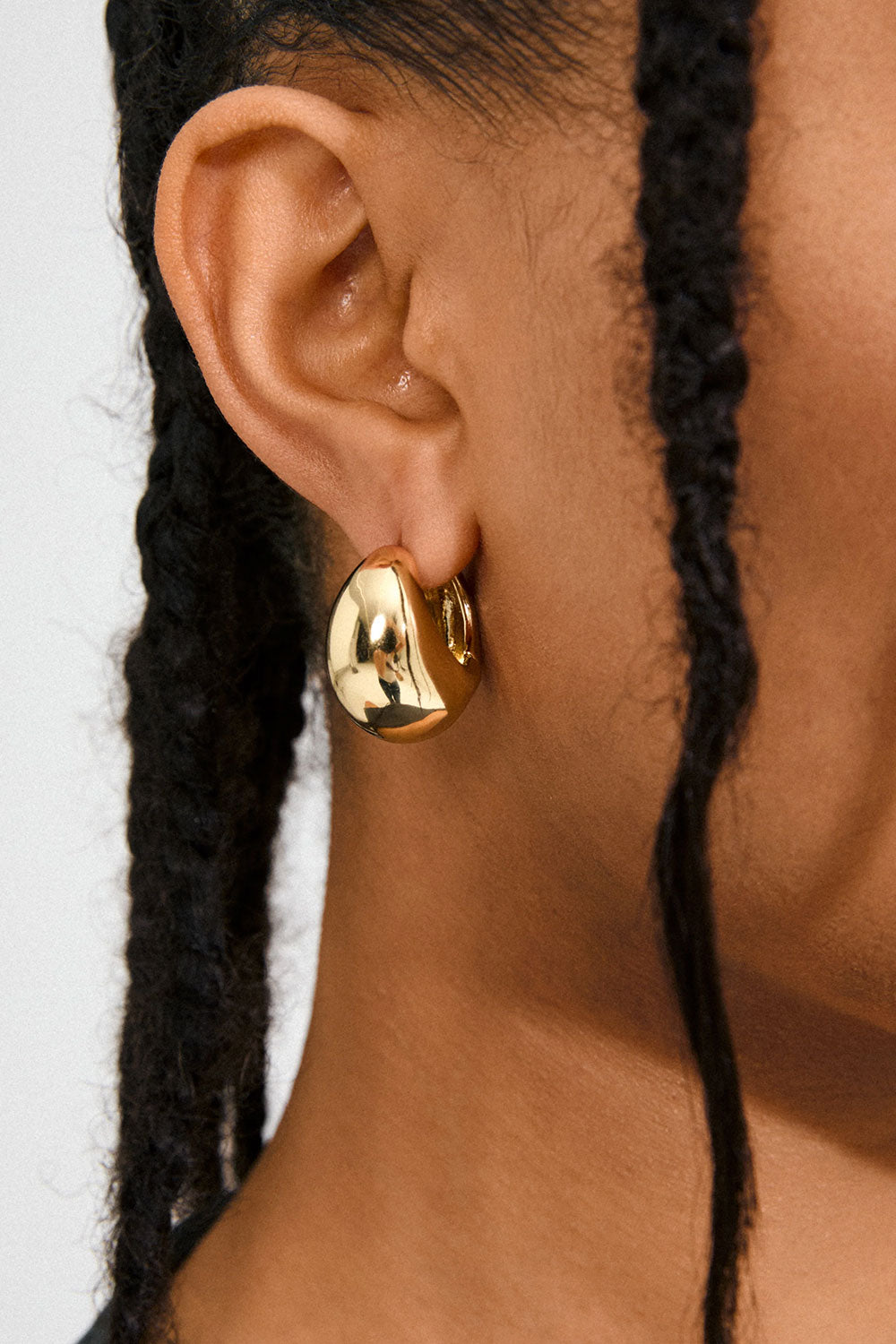 Close-up of a woman wearing a gold hoop earring Besi from Pilgrim available at la petie garçonne in Montreal.