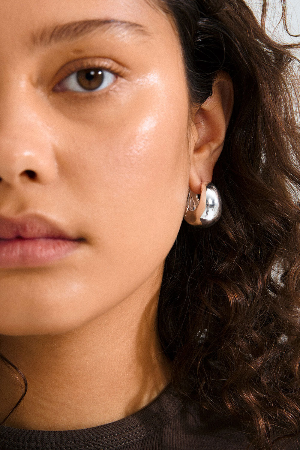 Photo of an ear wearing a silver hoop earring Besi from Pilgrim available at la petie garçonne in Montreal.