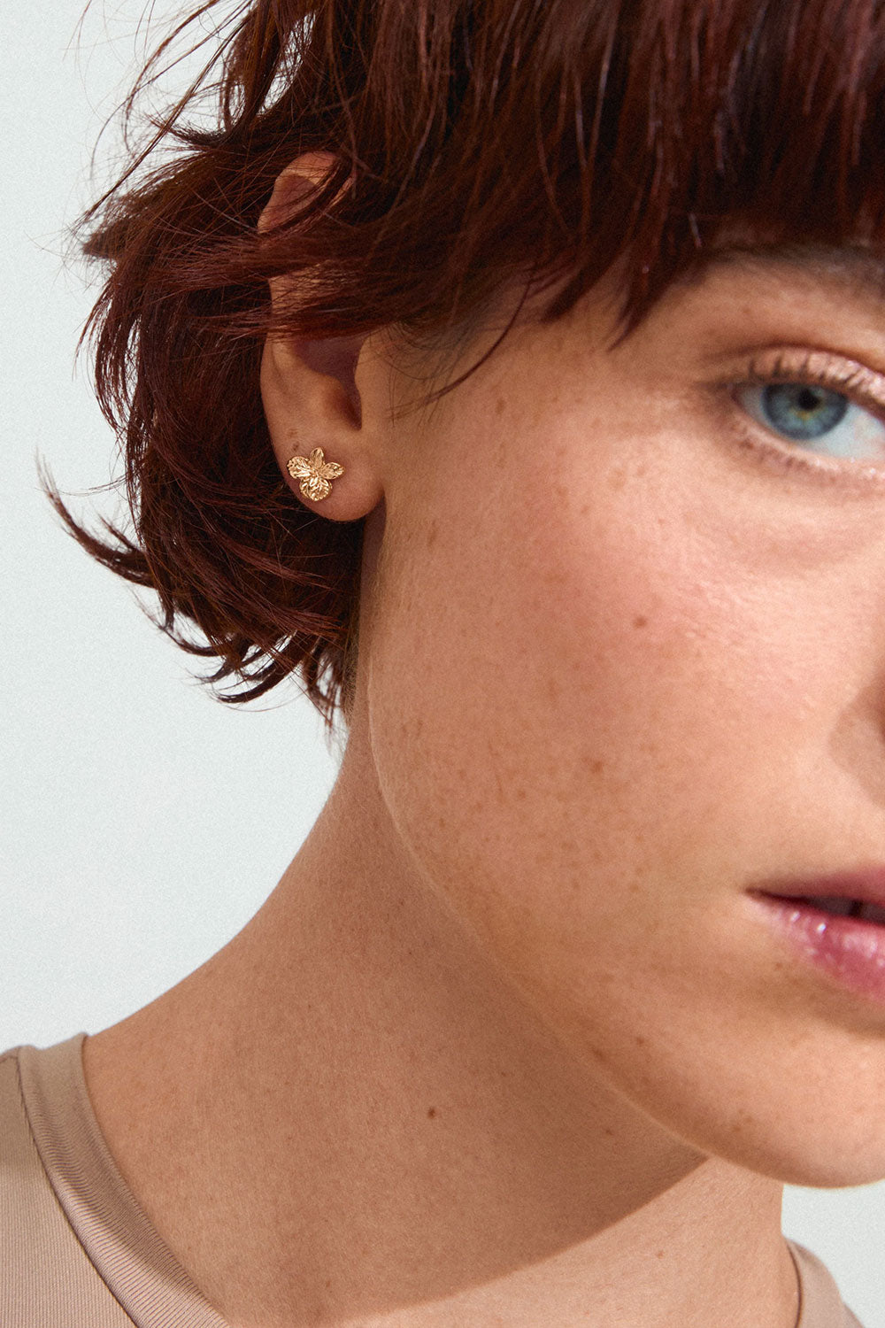 Close-up on a model of Charmaine from Pilgrim, a gold flower earring available at la petite garçonne in Montreal.