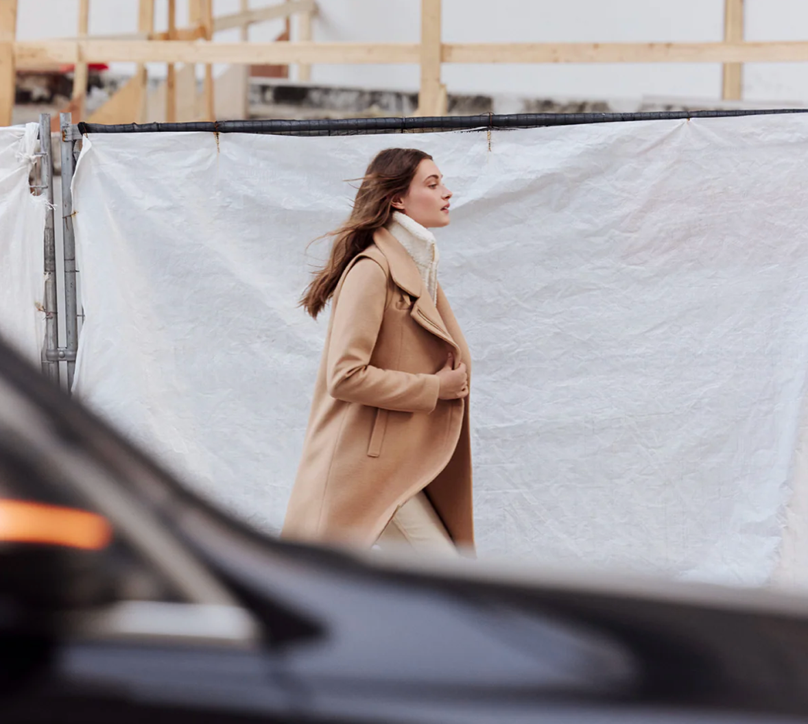 Woman in a beige coat Soia & Kyo standing behind a car