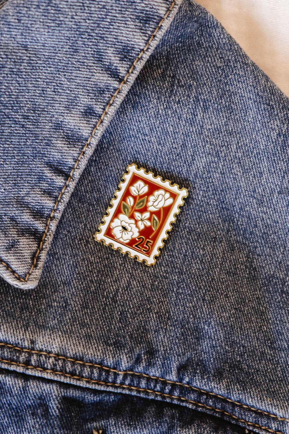 Decorative enamel pin with floral design from mimi and august on a denim jacket