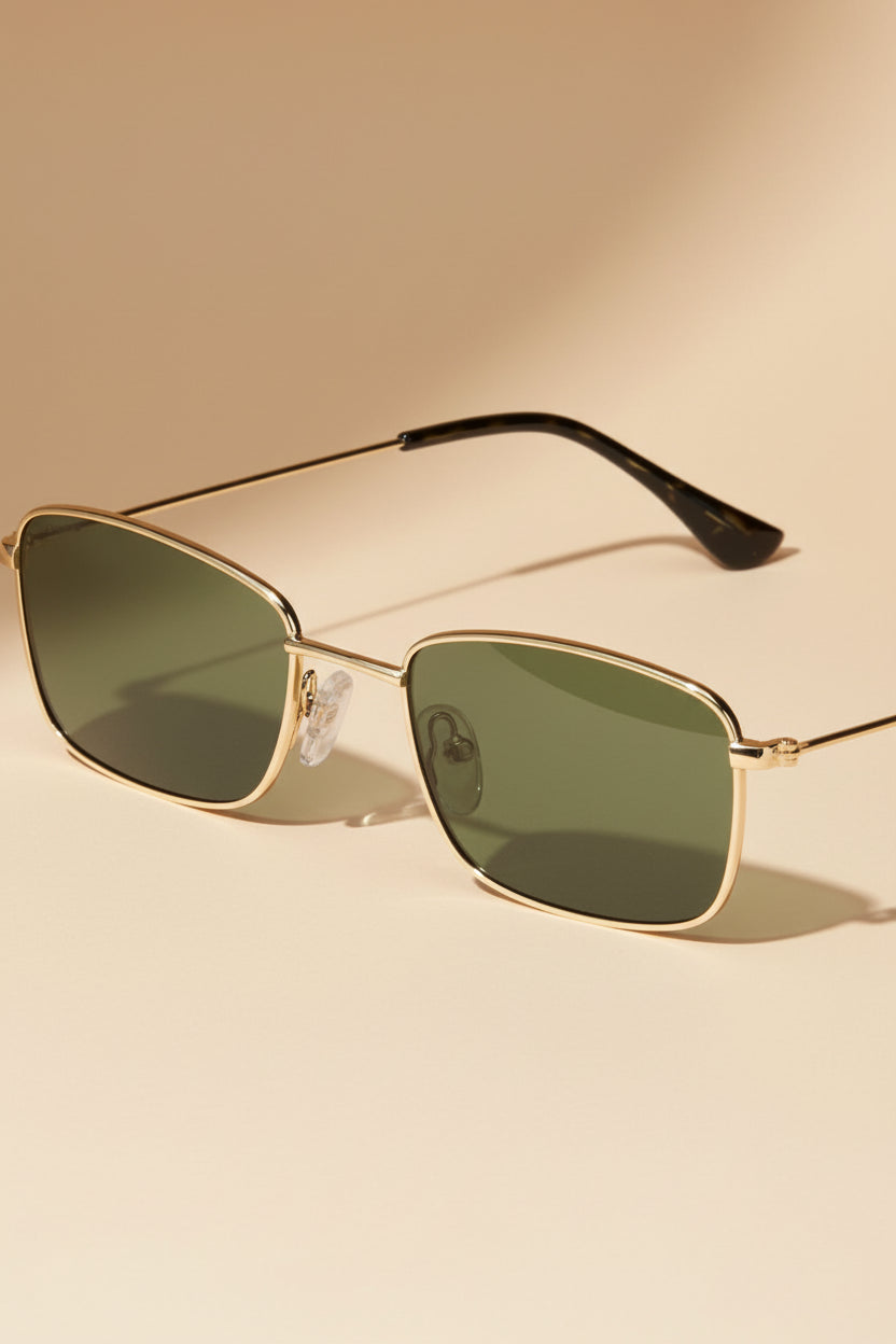 Sunglasses with gold frame and dark lenses by pilgrim on a white background