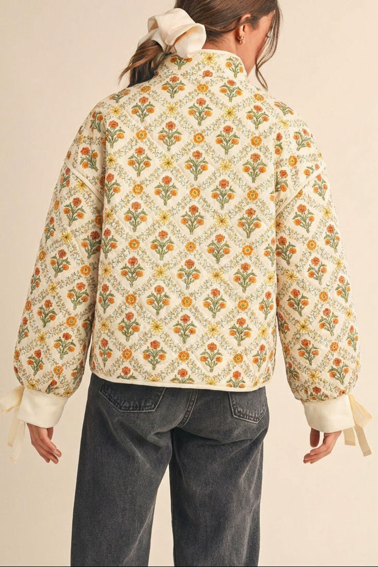 back view of a woman wearing Anabeth Orange Floral Quilted Jacket with Ribbon-Tied from Boutique 1861