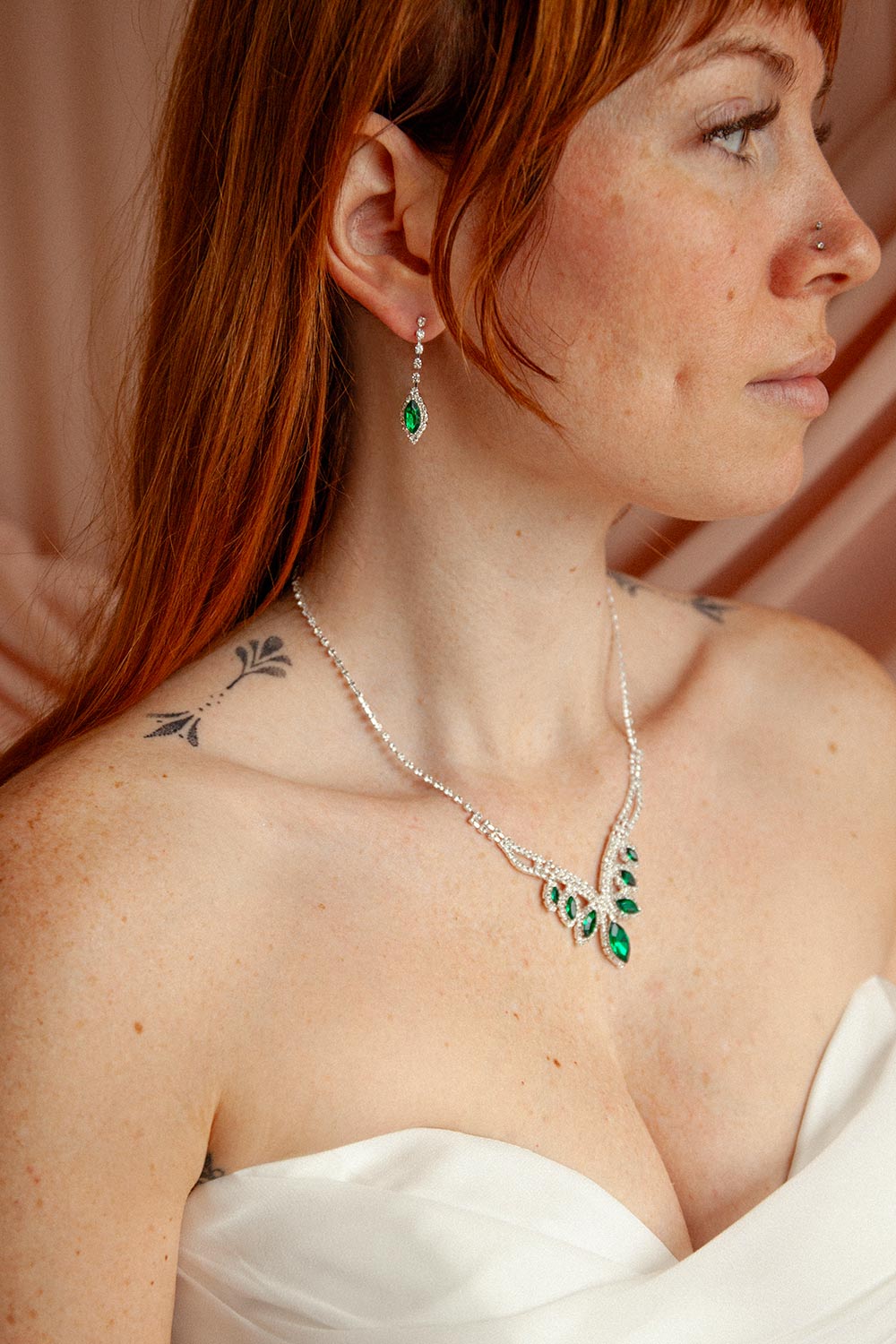 woman wearing emerald green gemstone earrings and a matching necklace called Artee from boutique 1861.