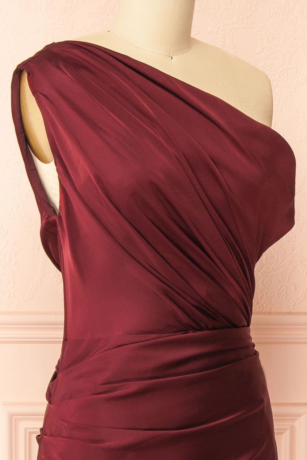 side of mannequin wearing Colleen Burgundy Asymmetrical Satin Dress from boutique 1861