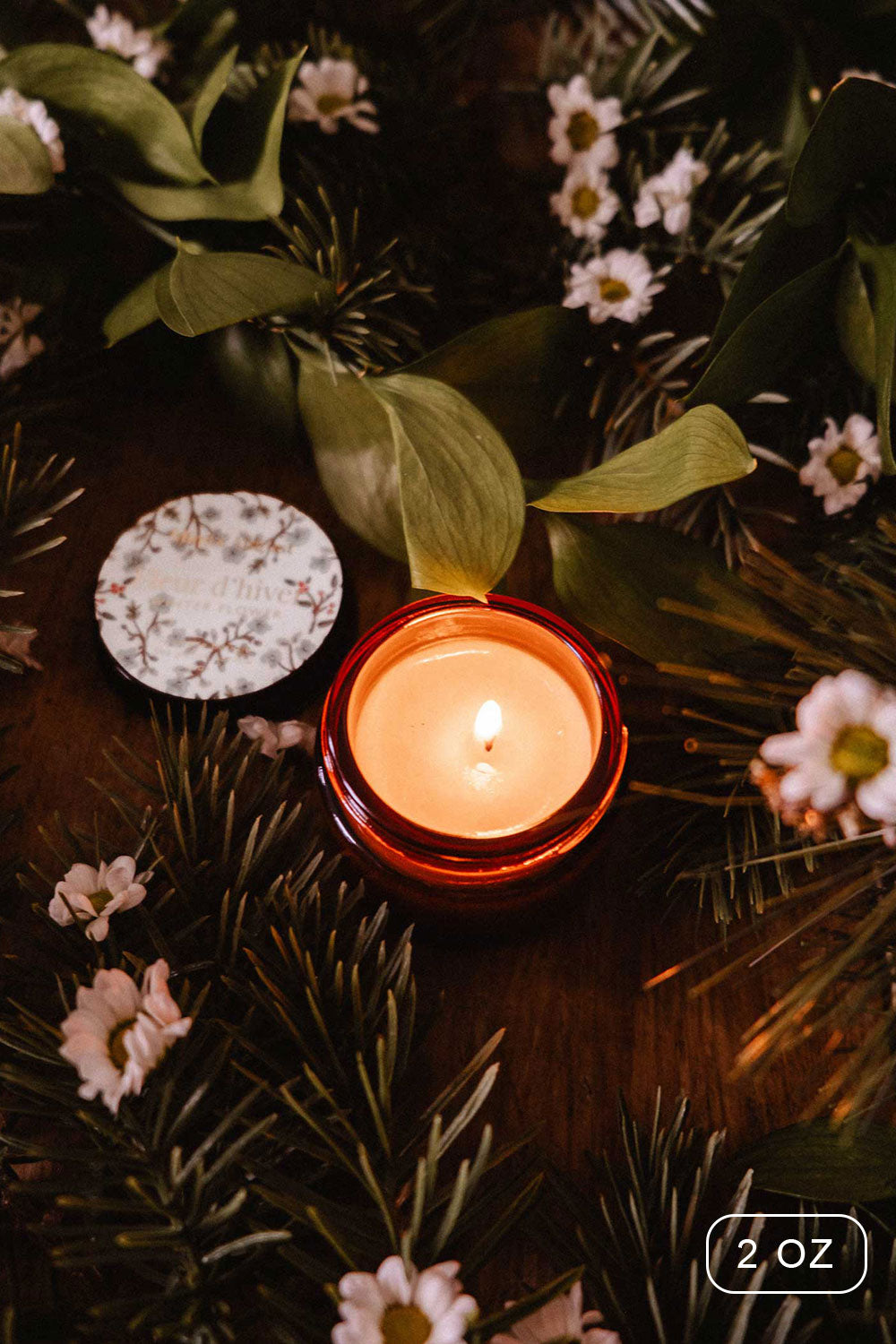 2oz Winter Flower Christmas Candle by Mimi and August with a decorative box on a bed of greenery and flowers