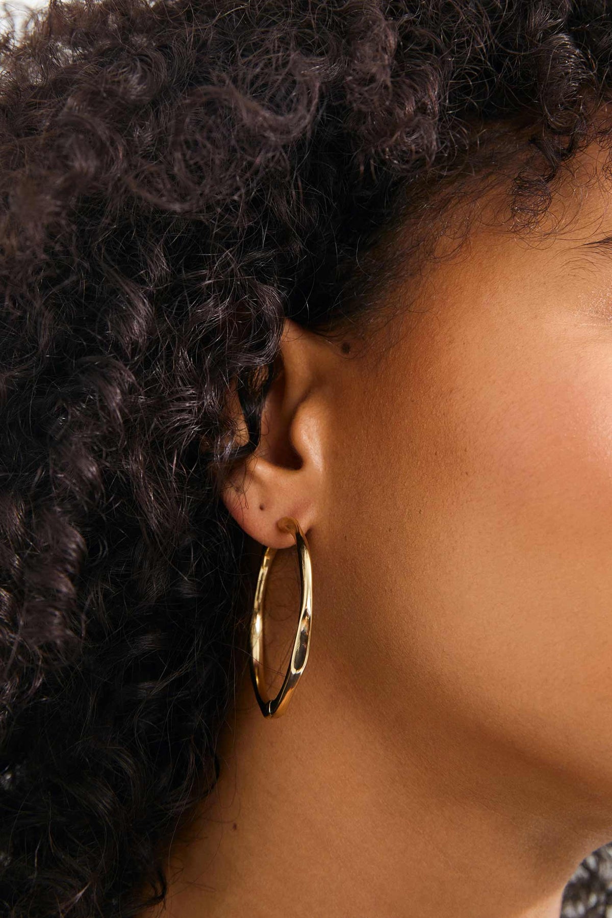 close-up of a woman wearing Edelia Gold Wave Hoop Earrings by Pilgrim from La petite garçonne