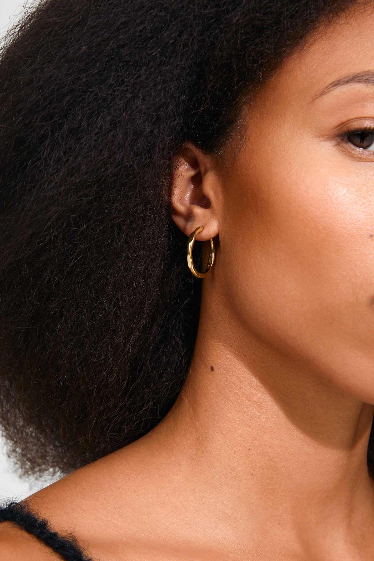 close-up of a woman wearing Eluda Gold Wave Hoop Earrings by Pilgrim from La petite garçonne