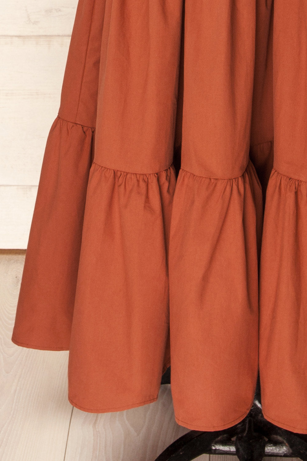 bottom of a mannequin wearing the Penrith Rust Mock Neck Midi Dress from boutique 1861