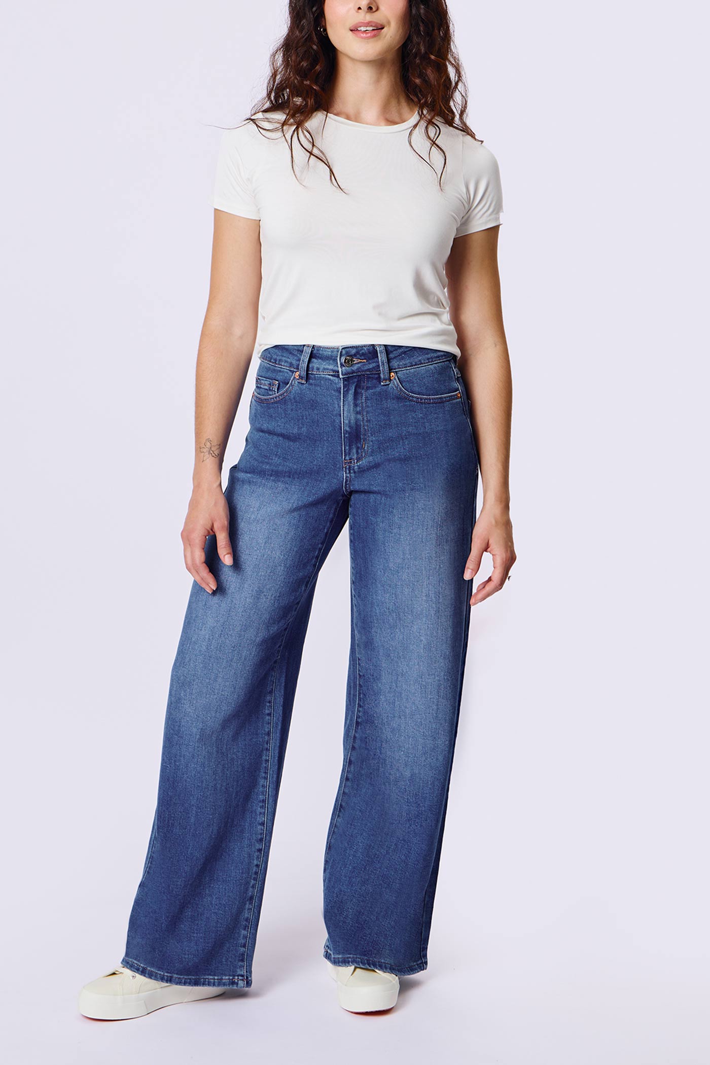 front of a woman wearing Aurora Jeans Blue High-Waisted Wide-Leg Jeans by Dailystory from La petite garçonne
