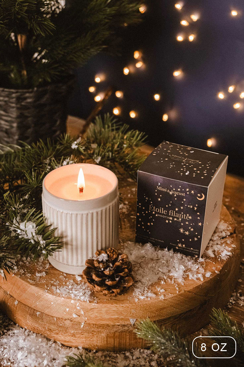 8 oz Shooting Star Christmas Candle by Mimi and August with a packaging on a wooden surface with decorative elements