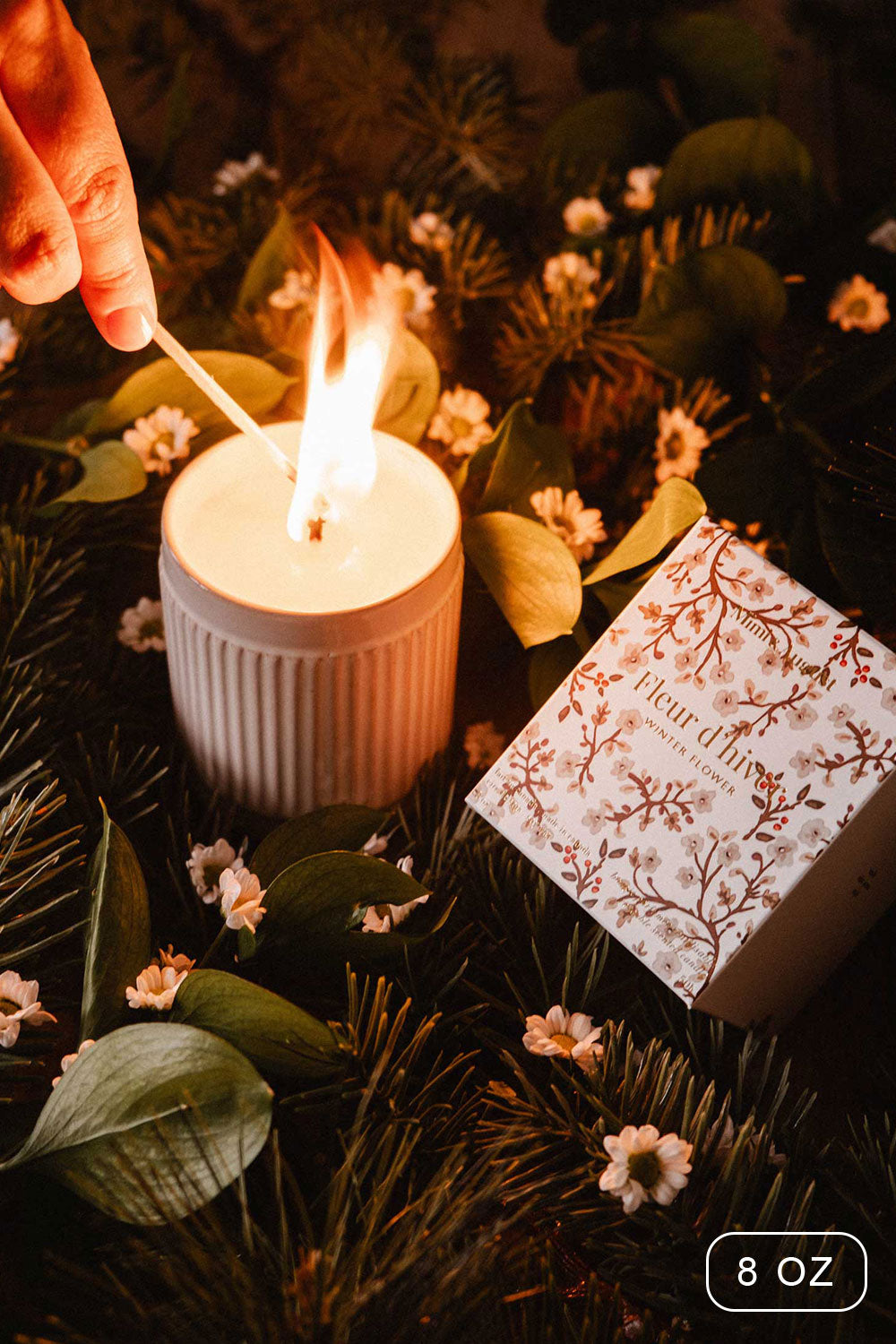 8oz Winter Flower Christmas Candle by Mimi and August with a decorative box on a bed of greenery and flowers