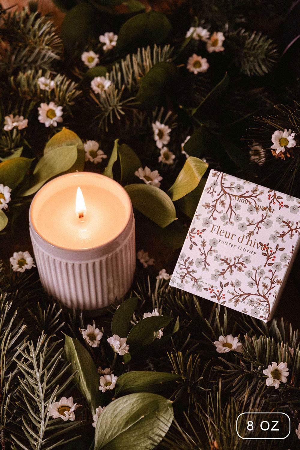 8oz Winter Flower Christmas Candle by Mimi and August with a decorative box on a bed of greenery and flowers