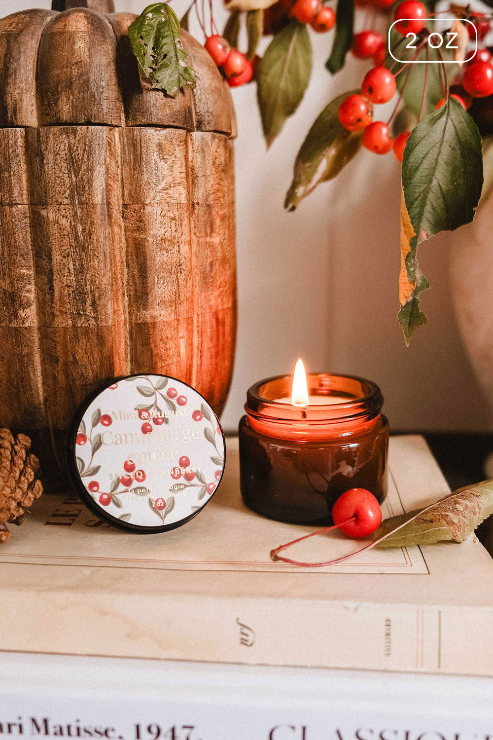 2 oz Spiced Cranberry Christmas Candle by Mimi & August and decorative box on books with a branch of berries 