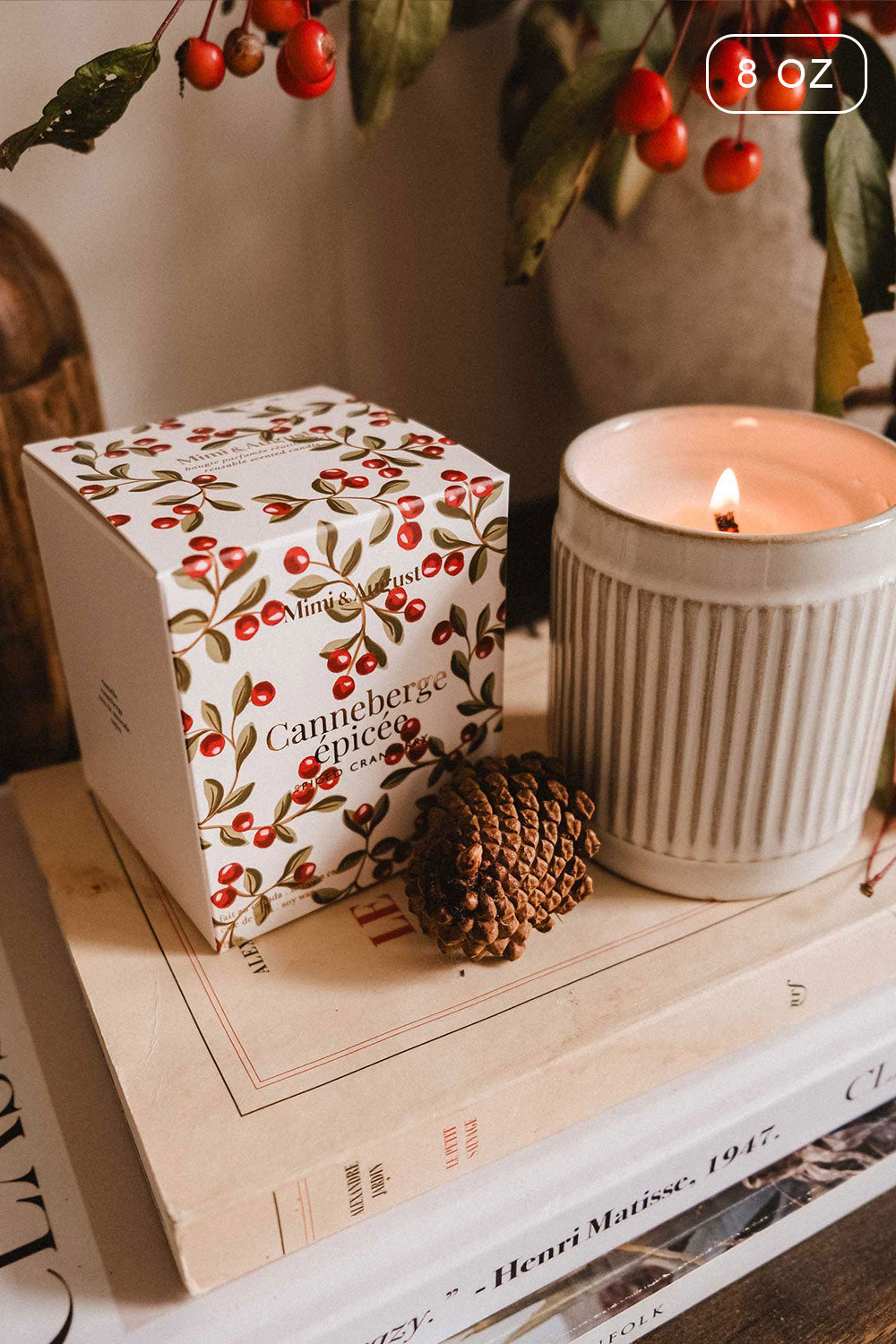 8 oz Spiced Cranberry Christmas Candle by Mimi & August and decorative box on books with a branch of berries 