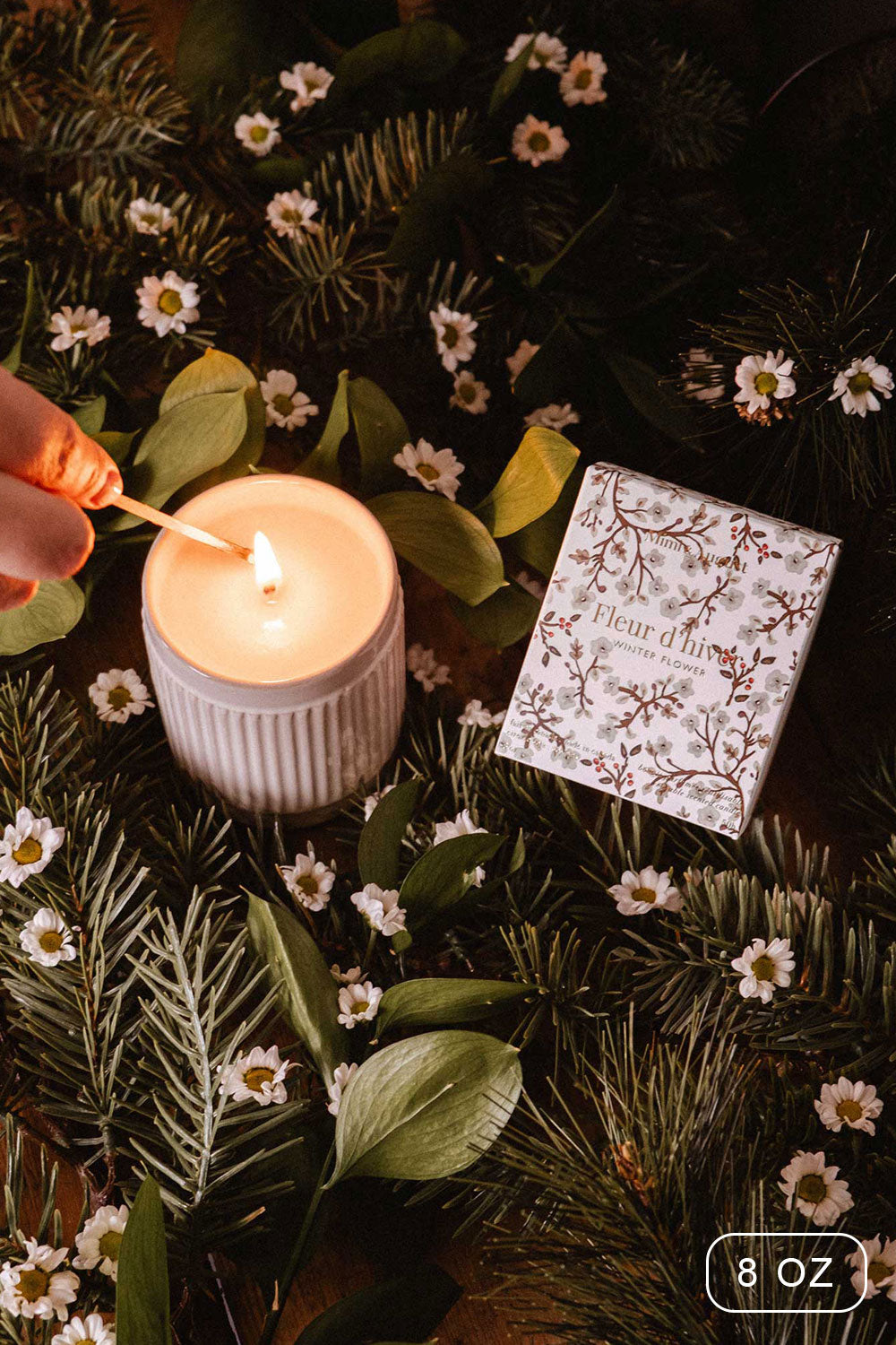 8oz Winter Flower Christmas Candle by Mimi and August with a decorative box on a bed of greenery and flowers