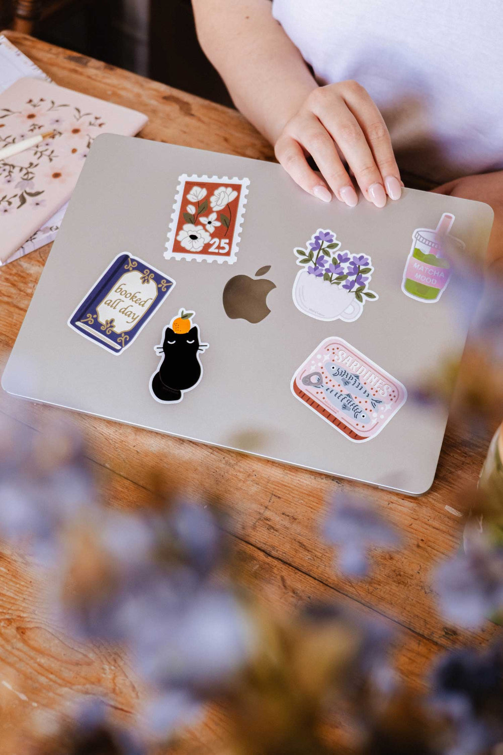Laptop with various stickers from Mimi and August on a wooden table