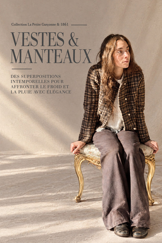 Une femme est assise sur une chaise à structure dorée devant un fond beige texturé, portant un manteau à carreaux bruns sur un haut blanc et un pantalon ample brun grisâtre. Un grand texte à gauche indique « MANTEAUX & VESTES », accompagné d’un texte de collection plus discret au-dessus.