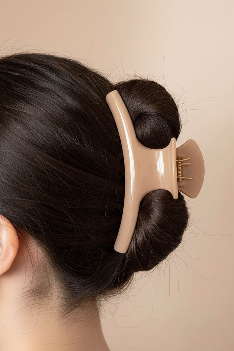 Biscuit Taupe hair clip holding a bun in dark hair against a beige background