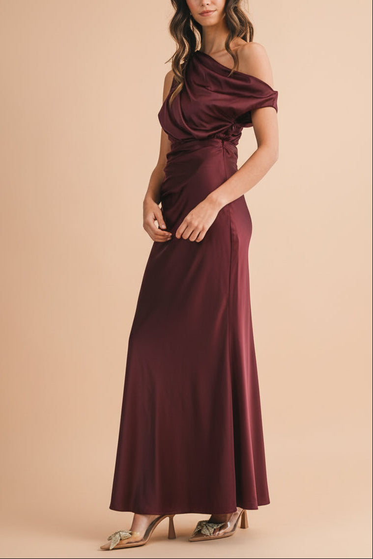 Sideview of a Woman wearing a Colleen Burgundy Asymmetrical Satin Dress from boutique 1861