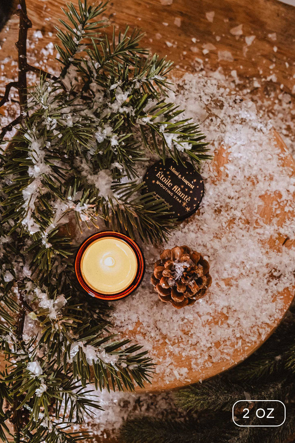 2 oz Shooting Star Christmas Candle by Mimi and August with a packaging on a wooden surface with decorative elements