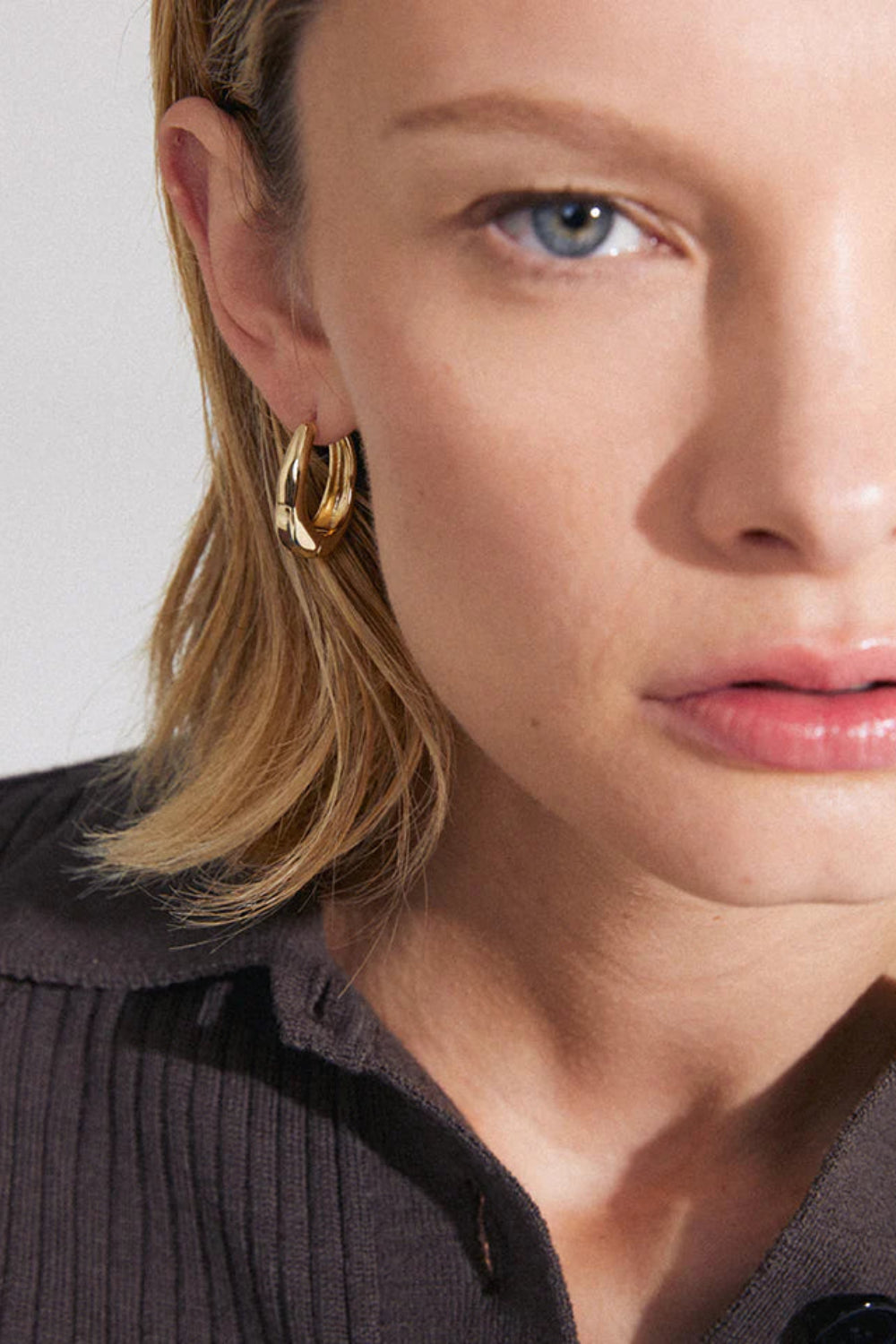 Close-up of a woman wearing Fevik Gold hoop earrings from Pilgrim available at la petite garçonne