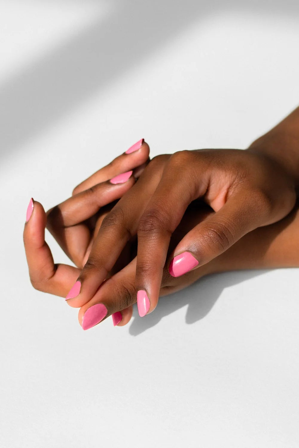 Solid pink color swatch on nails woman hands