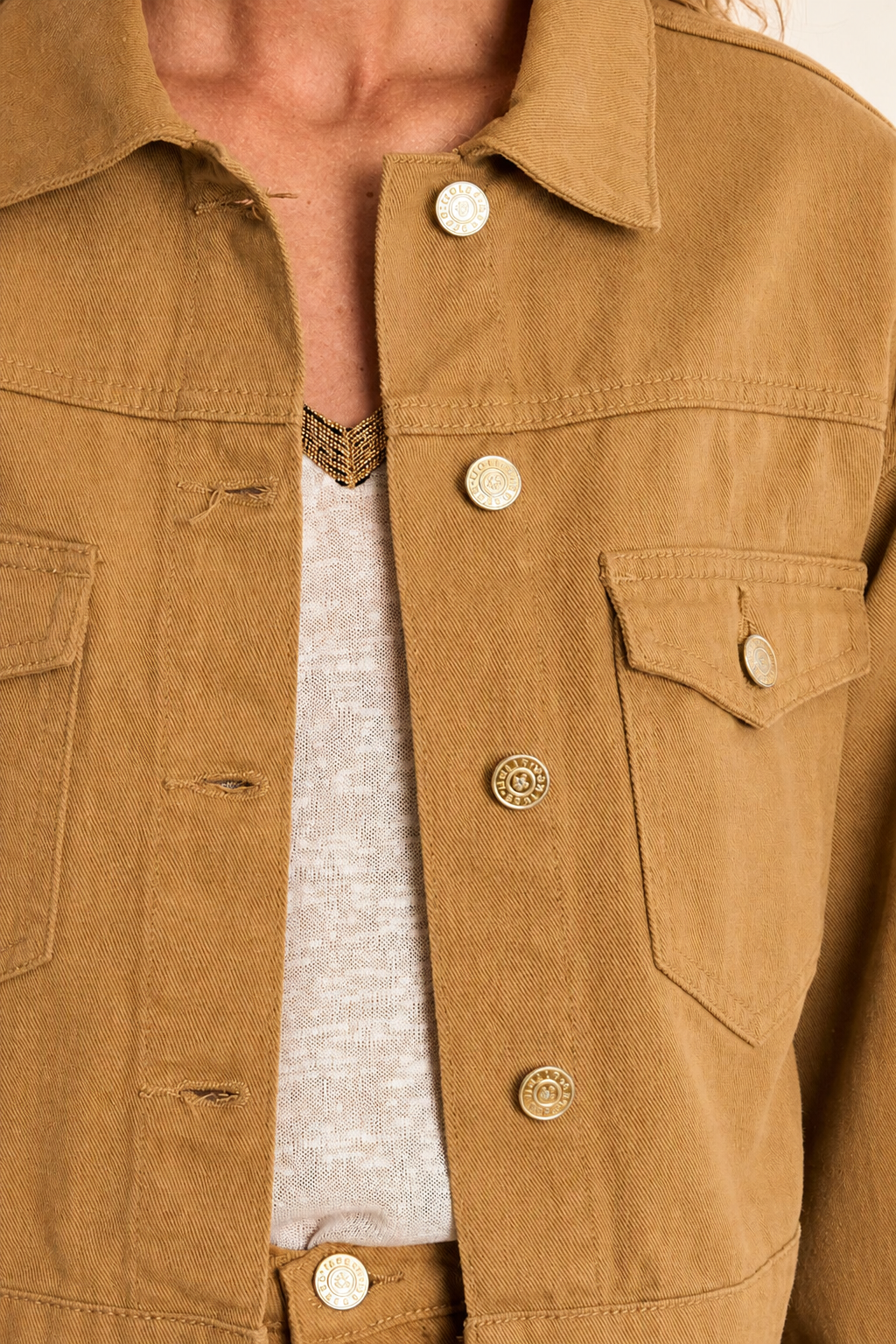 Close-up of a woman wearing Godhra Short Caramel Denim Jacket at la petite garçonne