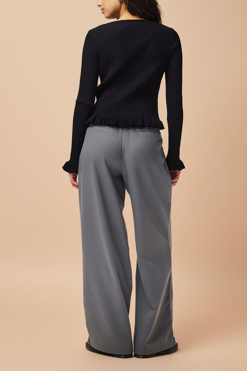 close back of a woman wearing Lortona Black Ribbed Knit Cardigan with Front Tie and Frill Details from La petite garçonne