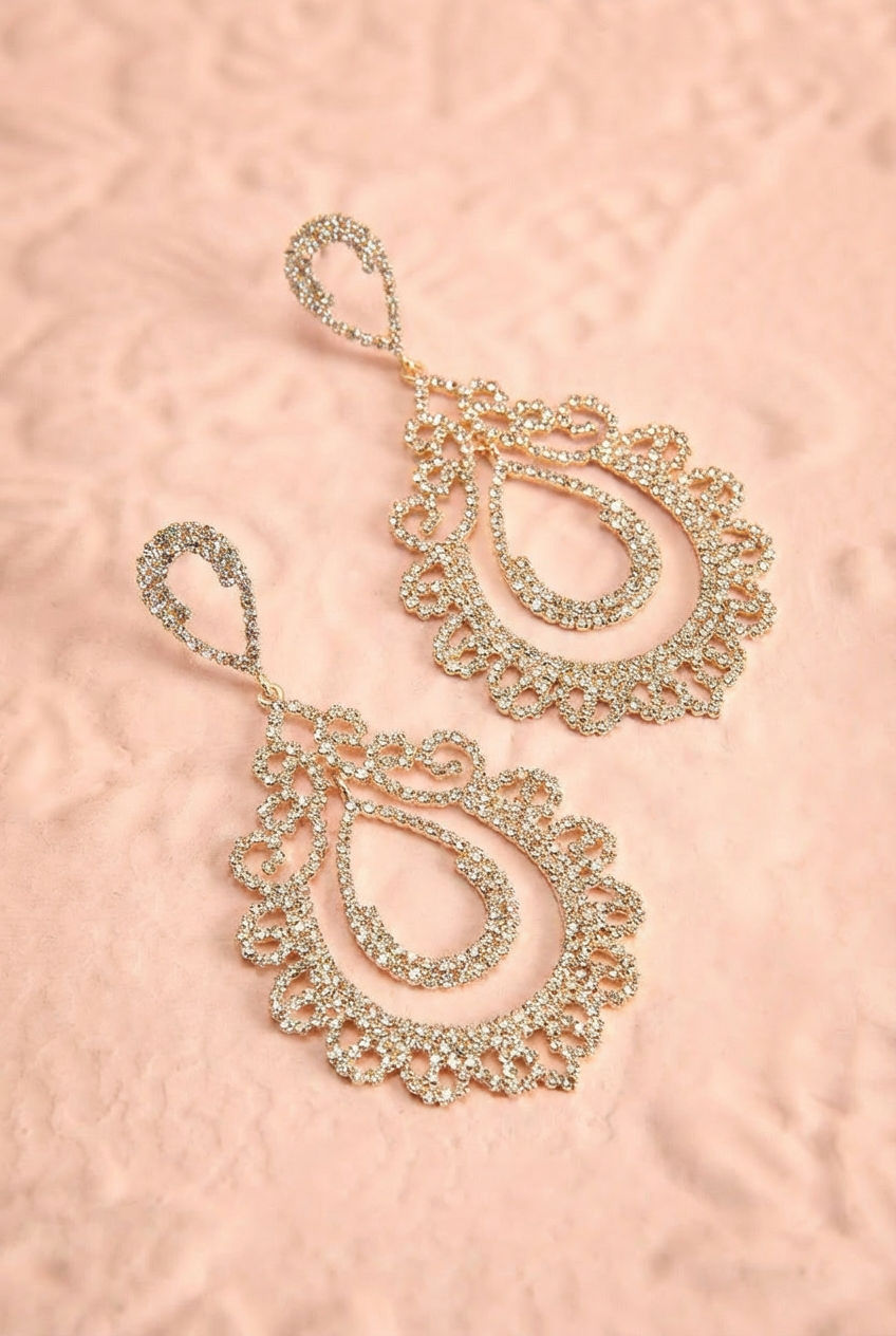 Top shot of a gold rhinestone layered teardrop dangle earrings shimmer with intricate, lace-like sparkle from boutique 1861