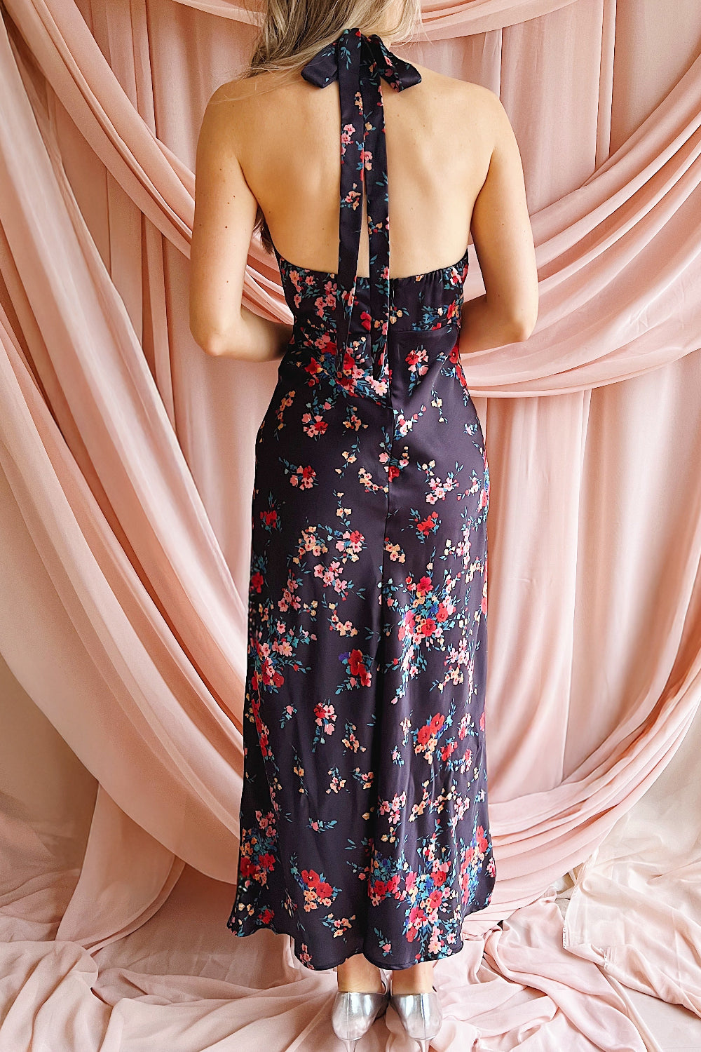 Woman wearing a floral dress with a pink draped curtain background